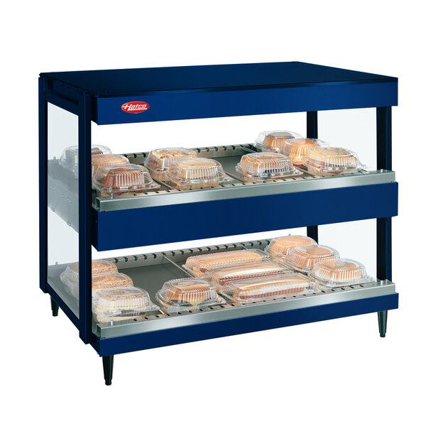 A blue Hatco countertop display case with trays of food.