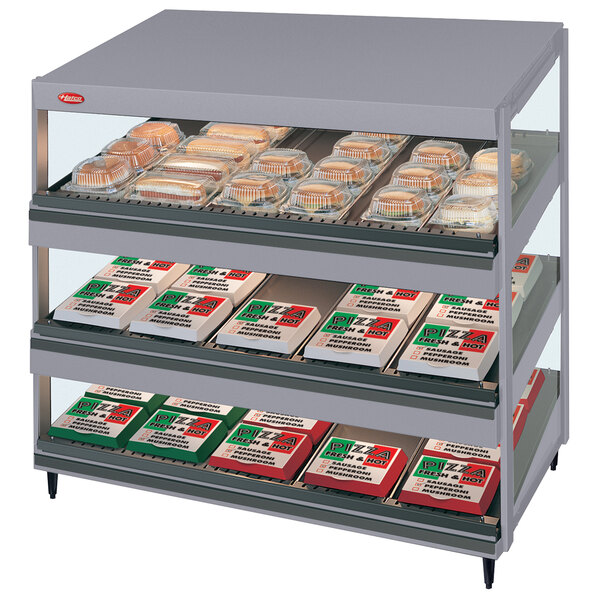 A Hatco countertop merchandiser with food on three slanted shelves.