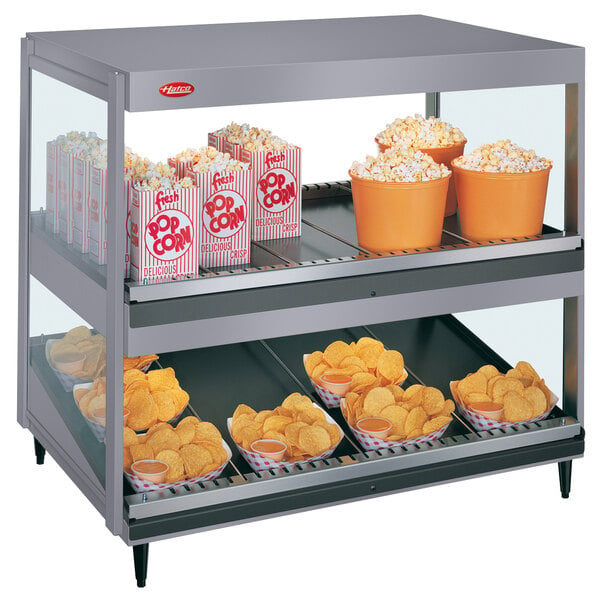 A large display case with a bowl of potato chips and a bucket of popcorn.