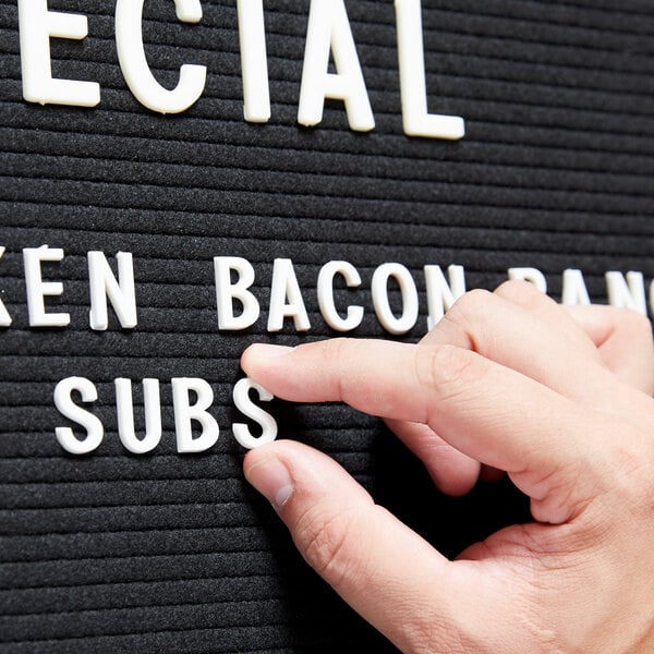 A person using Aarco Helvetica sign letters to point to a sign that says "Special Bacon Subs"