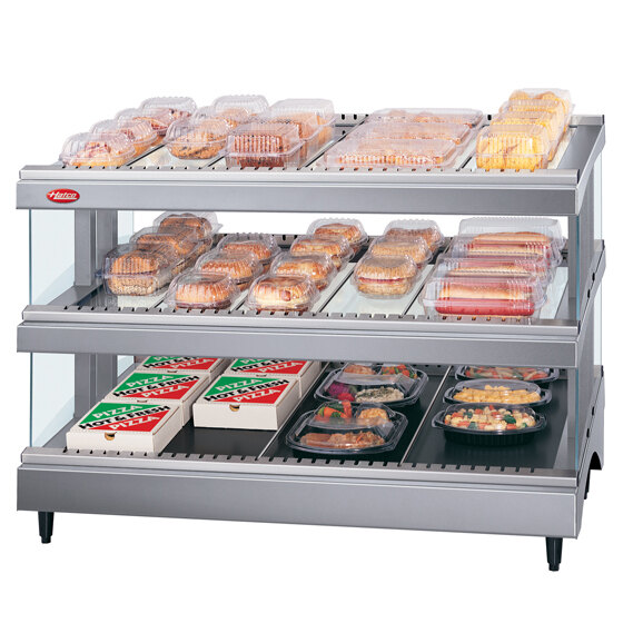 A Hatco countertop heated glass merchandising warmer with food on shelves.