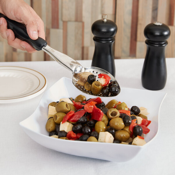 A person using a Vollrath perforated basting spoon to serve olives from a bowl.
