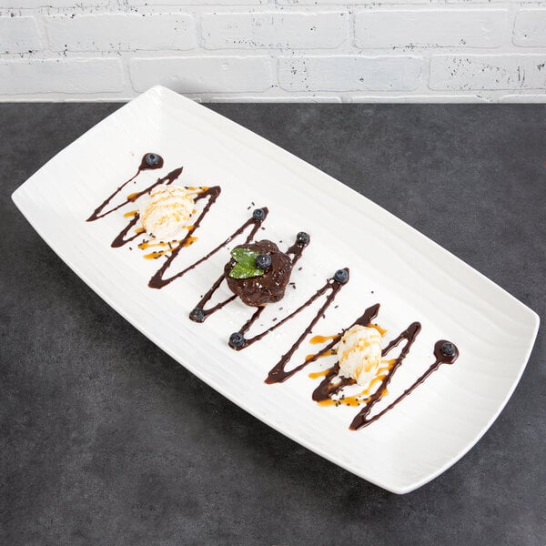 A 10 Strawberry Street Whittier white rectangular porcelain platter with a dessert with ice cream and chocolate sauce.