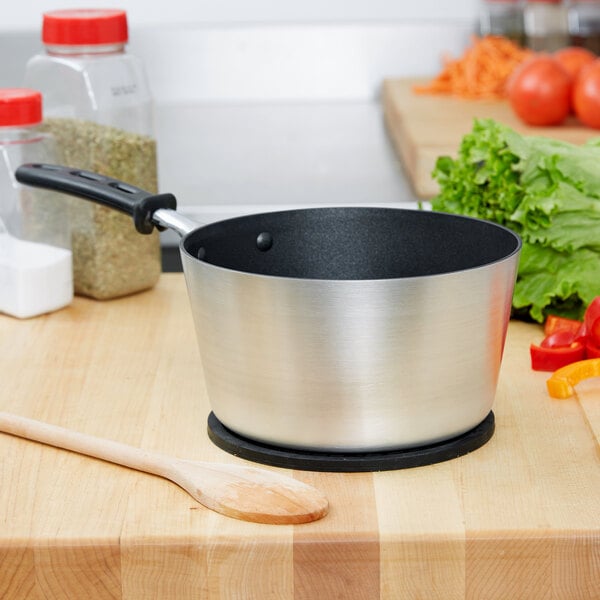 A Vollrath Wear-Ever sauce pan with a black handle on a black surface.