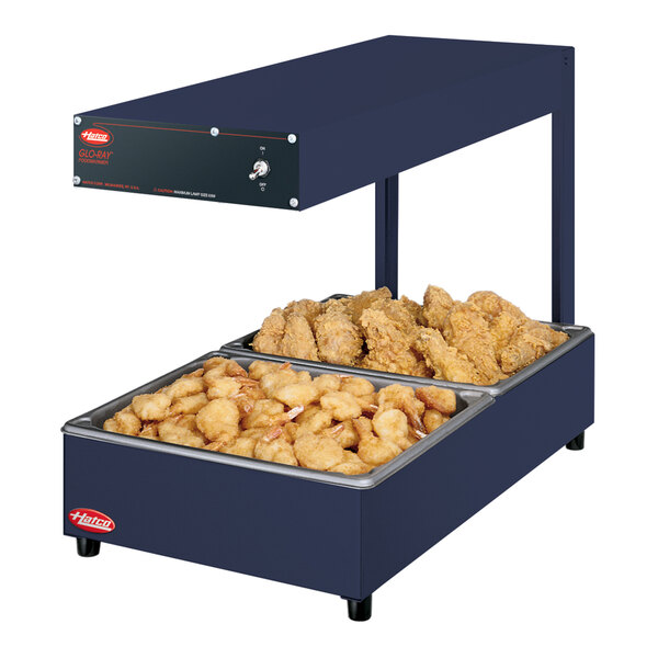 A Hatco navy blue portable food warmer with two trays of chicken and fries over a deep fryer.