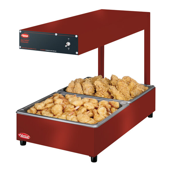A red Hatco Glo-Ray food warmer with chicken and fries on a tray.