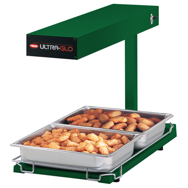 A green Hatco Ultra-Glo food warmer on a counter with trays of tater tots.