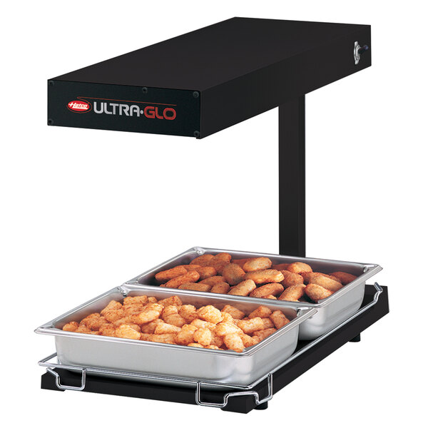 A black Hatco Ultra-Glo food warmer heating trays of food on a table.