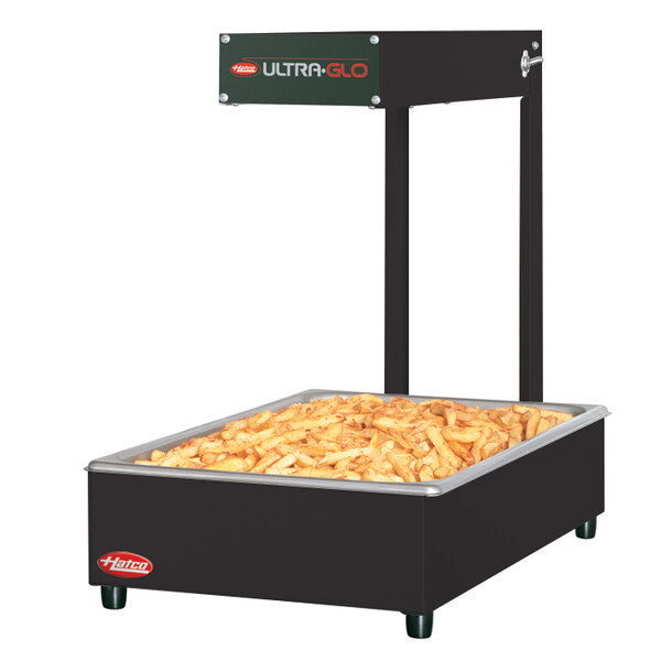 A black Hatco food warmer with french fries on top on a table outdoors.