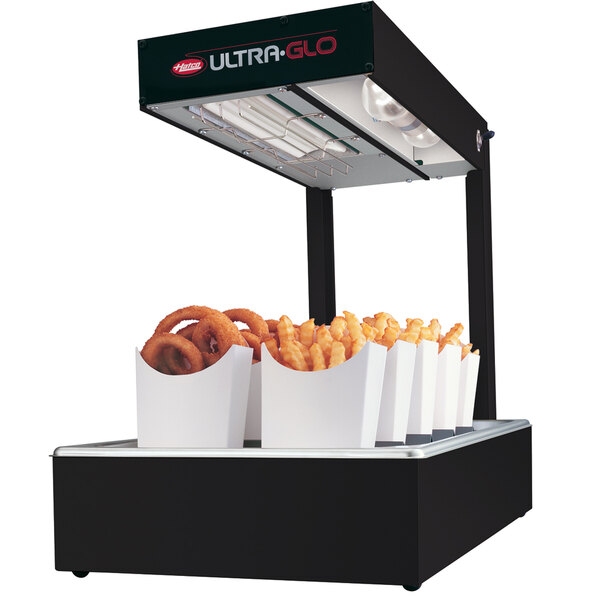 A Hatco Ultra-Glo food warmer on a counter with french fries and onion rings in food trays.