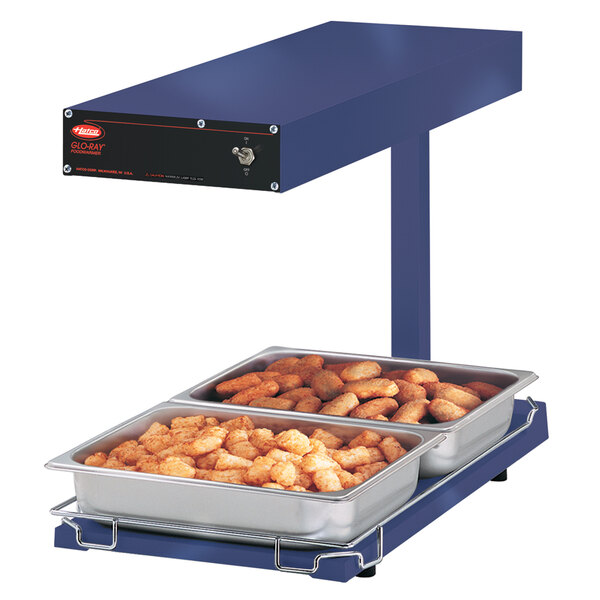 A Hatco blue portable food warmer with trays of chicken nuggets on it.