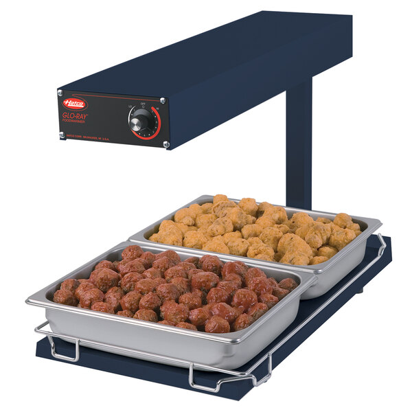 A Hatco navy blue heated food warmer with trays of meatballs and chicken on a table.