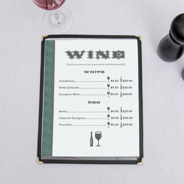 A green woven border menu with a glass of wine on it on a table.