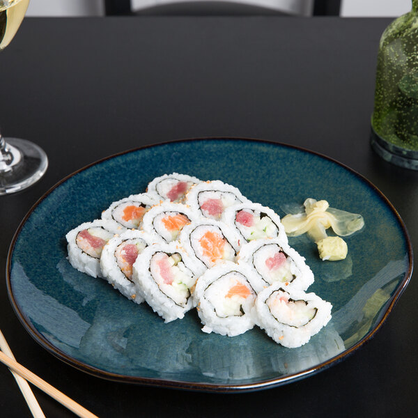 A Tuxton Artisan china plate with sushi and chopsticks on a table.