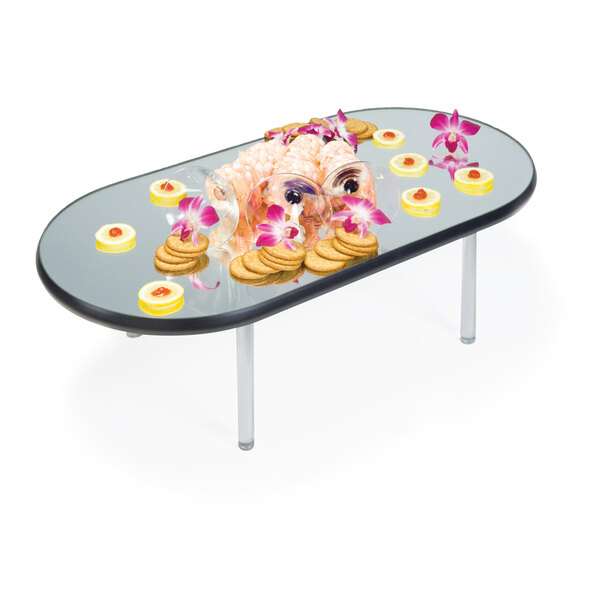 A Geneva oval rimless mirror food display tray on a table with food and flowers.