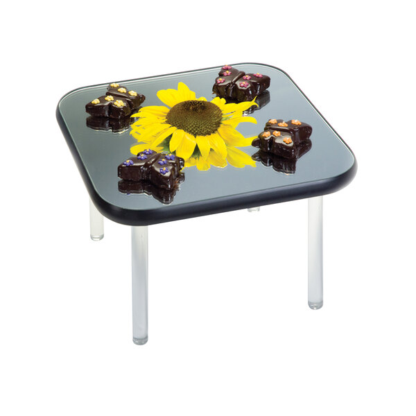 A Geneva square rimless mirror food display tray on a table with chocolate butterflies and a sunflower.