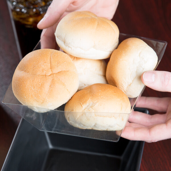 A person holding a container of bread with American Metalcraft PET bowl and basket liners inside.