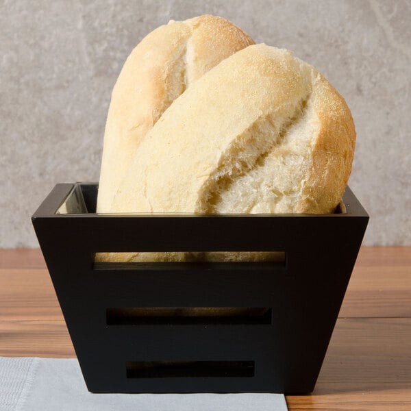 Two loaves of bread in a square birch bread basket.