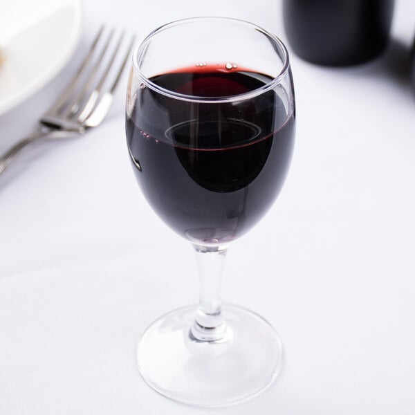 An Arcoroc wine glass filled with red wine on a table.