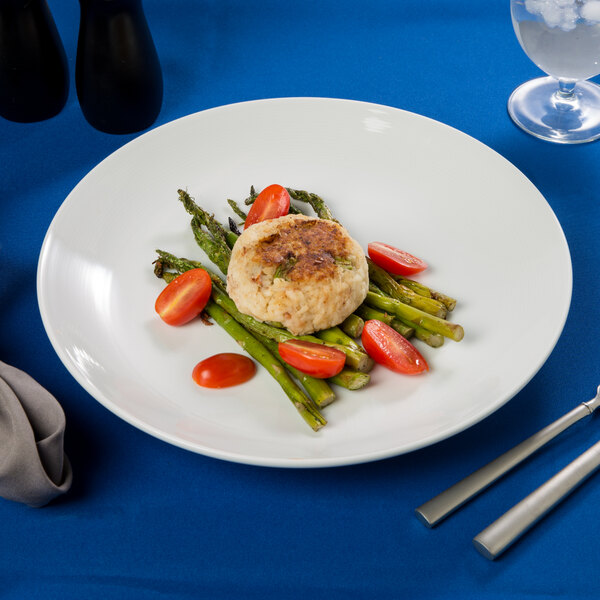 A Arcoroc Rondo porcelain plate with asparagus and tomatoes on a table.