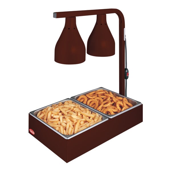 A Hatco Antique Copper countertop food warmer with two bulbs above a tray of fries.