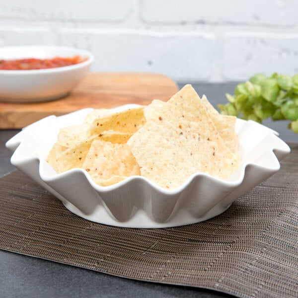 A white 10 Strawberry Street Whittier ruffle bowl filled with chips on a place mat.