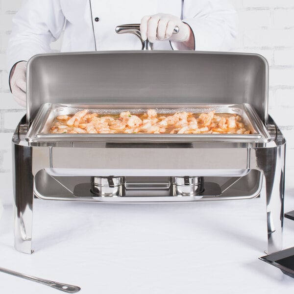 A person cooking shrimp in a Vollrath stainless steel chafing dish on a table outdoors.