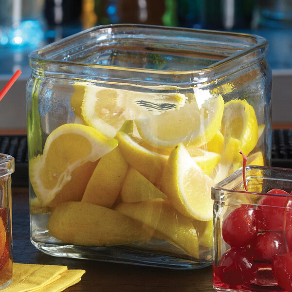 An American Metalcraft square glass condiment jar filled with lemons and cherries.