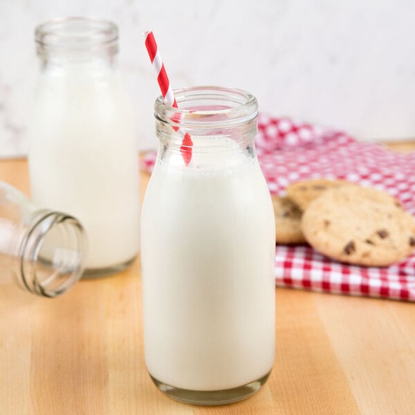 An American Metalcraft glass milk bottle with milk and a straw.