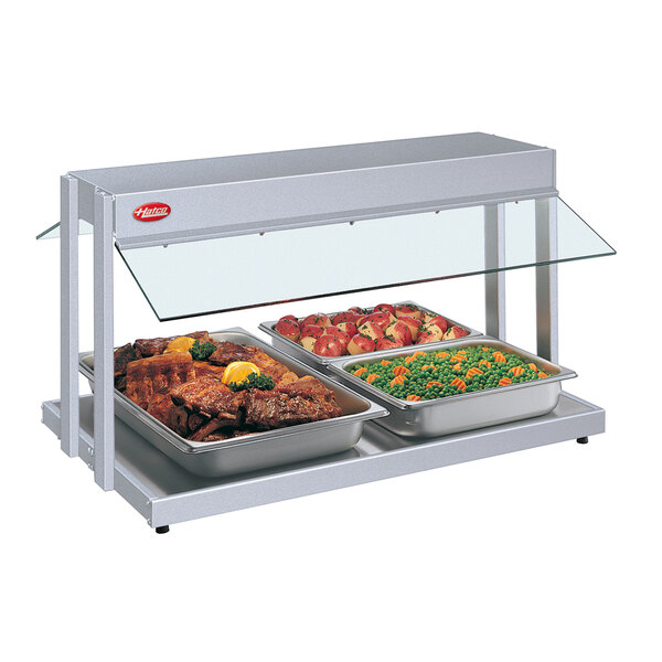 A Hatco countertop buffet warmer with three trays of food including meat, vegetables, and peas and carrots.