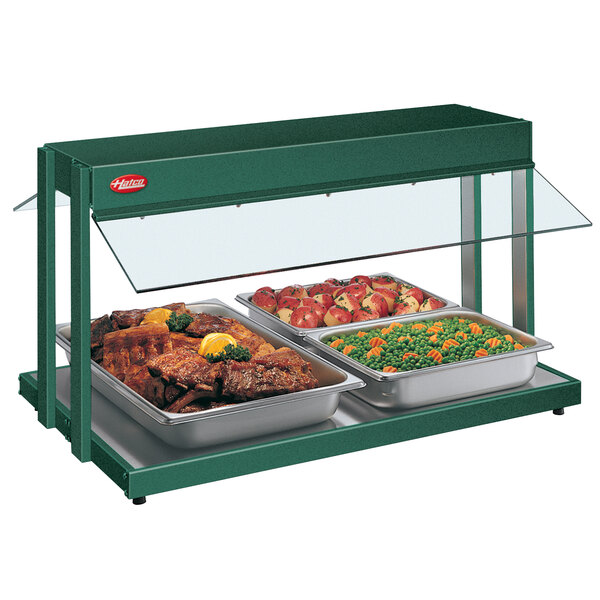 A Hatco green countertop food warmer with trays of meat and vegetables.
