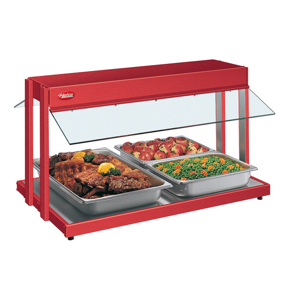A Hatco red countertop buffet warmer with trays of meat and vegetables.