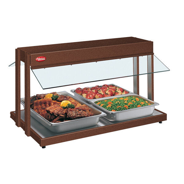 A Hatco countertop buffet warmer with trays of meat, peas, and carrots, and red and white food.