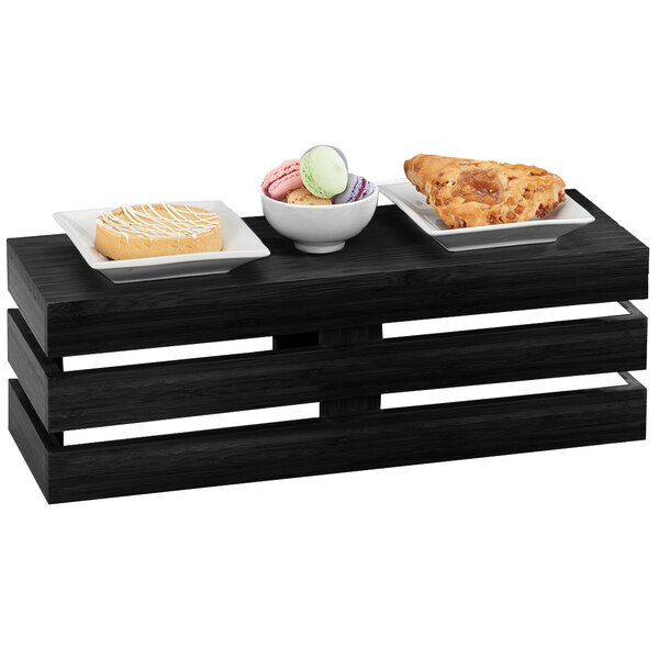 A black wooden Cal-Mil rectangle crate riser holding different types of food on a table in a bakery display.