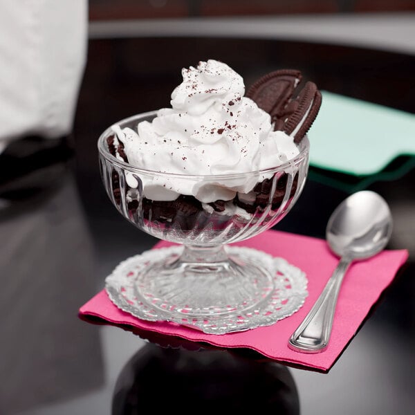 An Arcoroc swirl optic dessert dish filled with a dessert topped with whipped cream and cookies.