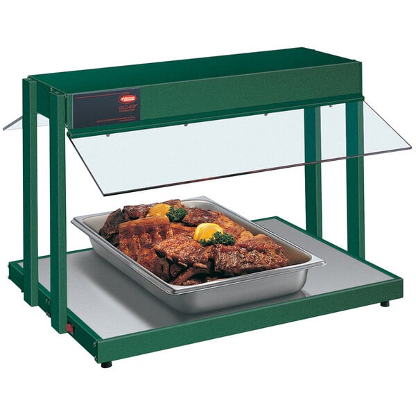 A Hatco green countertop buffet warmer with a tray of meat and lemon wedges.