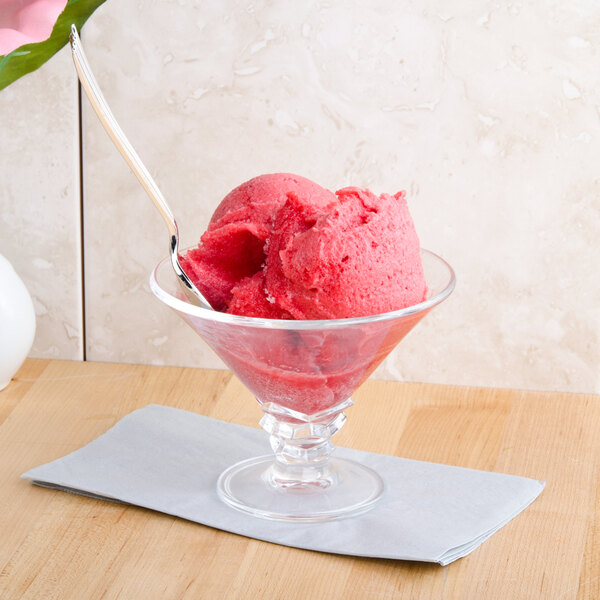 A Arcoroc glass dessert dish with a scoop of pink ice cream.