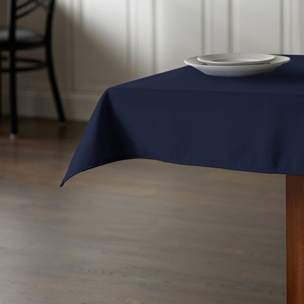 A table with a navy blue Intedge tablecloth and a plate on it.