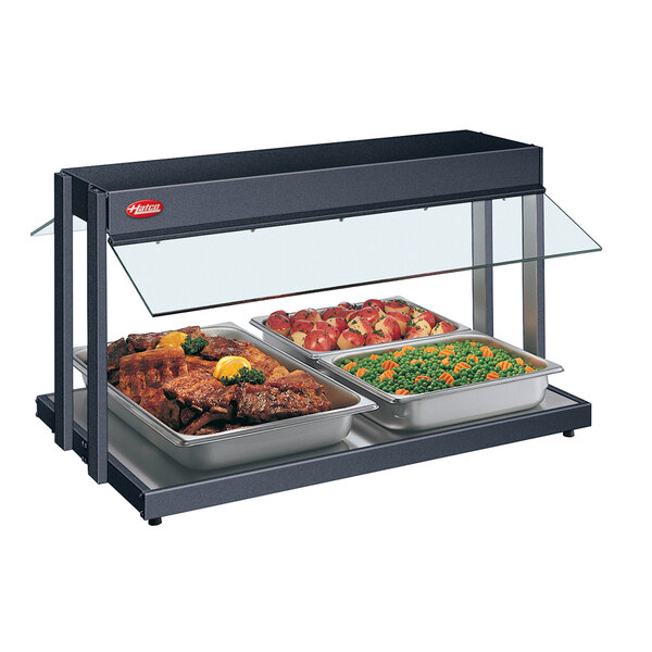 A Hatco buffet warmer with two trays of food, including meat and vegetables.