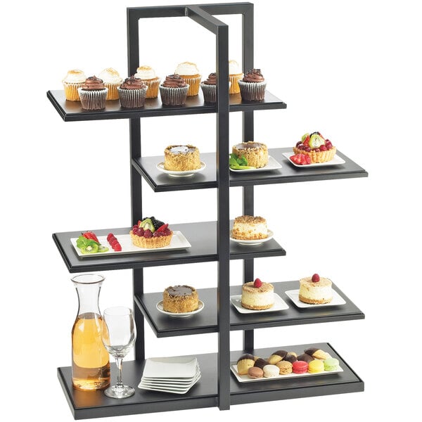 A black Cal-Mil multi-level shelf display with desserts on each shelf.