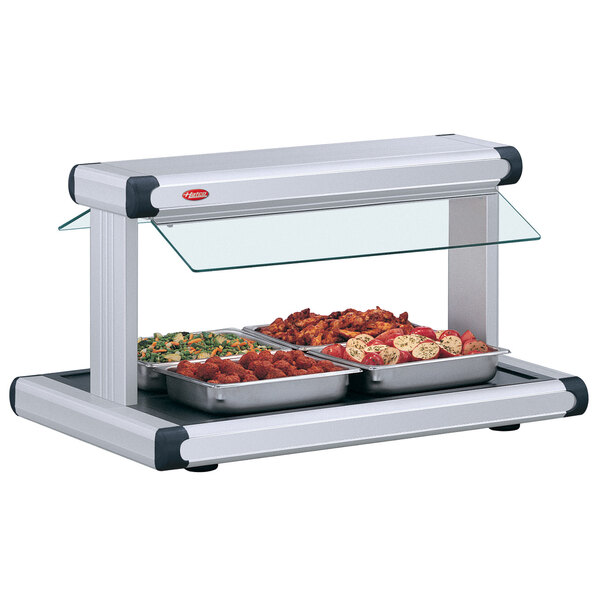A Hatco buffet food warmer with white granite insets and trays of food on a buffet counter.