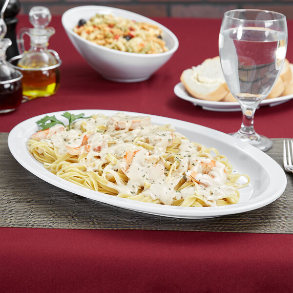 A white oval platter with pasta, shrimp, and vegetables on it.