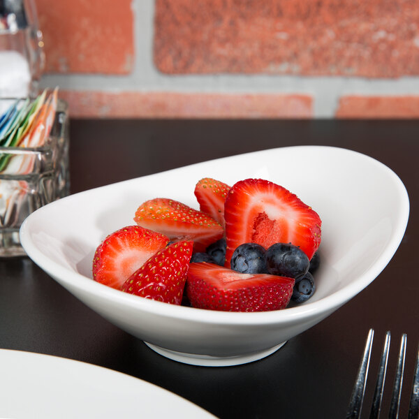 A Tuxton Pearl White China bowl filled with strawberries and blueberries on a table.