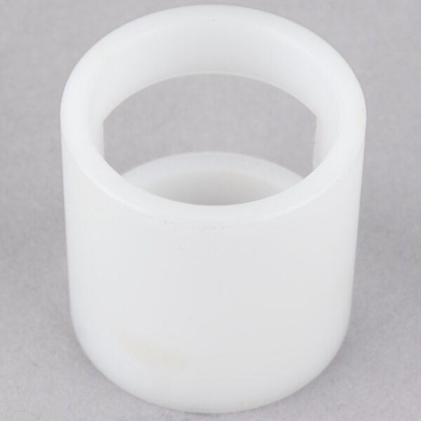 A white plastic slotted bushing with a hole in the middle.