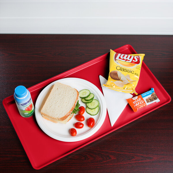 A red Cambro dietary tray with a sandwich, vegetables, and a drink on it.