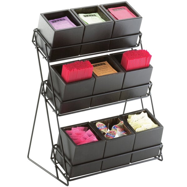 A black metal Cal-Mil tiered display rack on a counter holding different items.