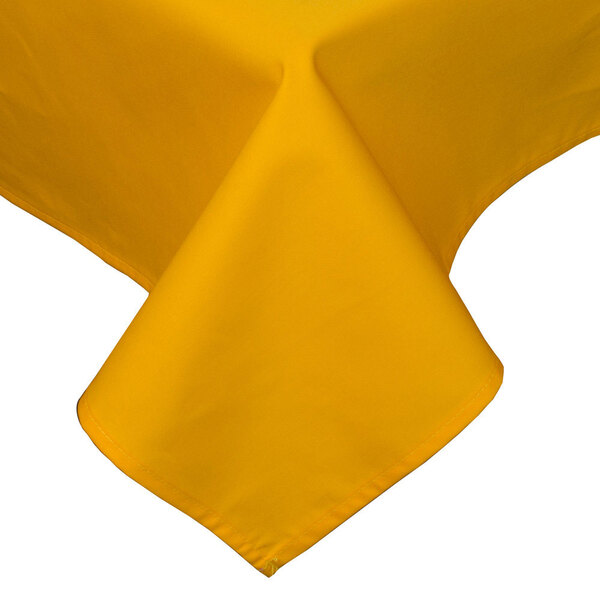 A gold rectangular tablecloth with a folded edge on a table