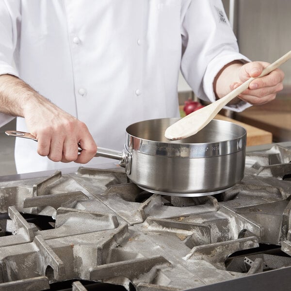 A chef stirring food in a Vollrath Centurion saute pan on a stove.