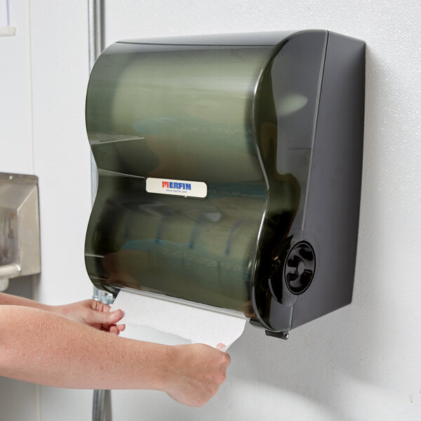 A person using a Merfin hands-free paper towel dispenser.