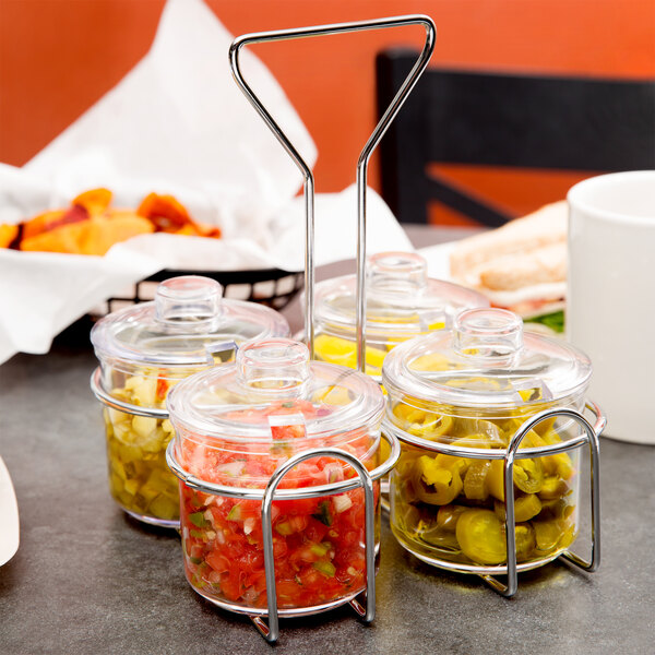 A Thunder Group wire condiment jar holder on a table with jars of food.